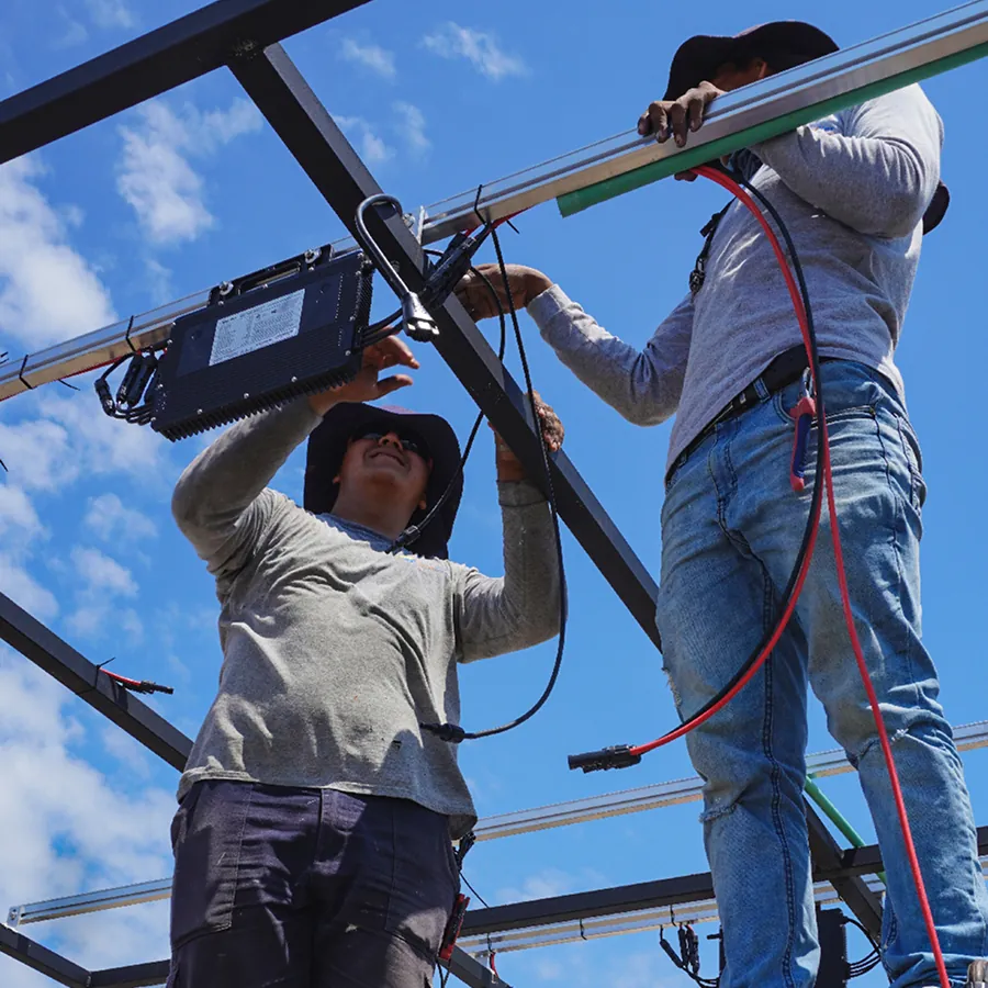 Cuadrilla de Solarver montando un panel sobre la estructura de una azotea, con la ciudad al fondo.