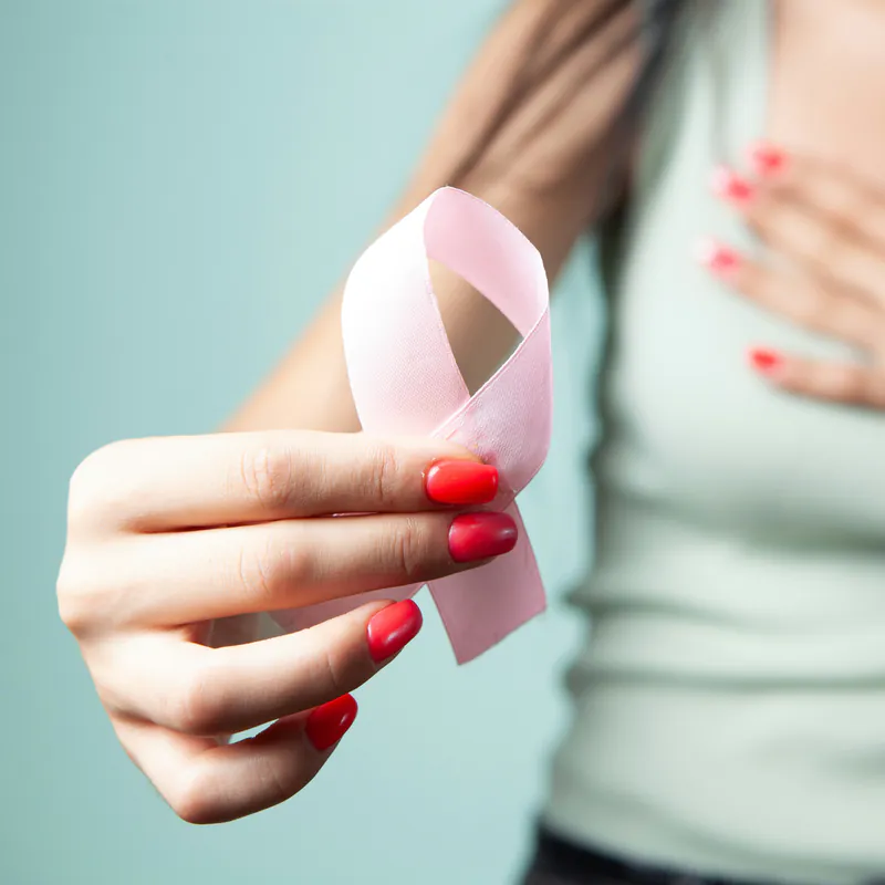 Una mujer sostiene un listón rosa, símbolo de la lucha contra el cáncer de mama.