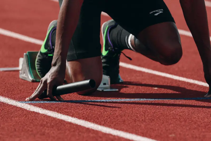 Un velocista en posición de salida sobre la pista de atletismo.